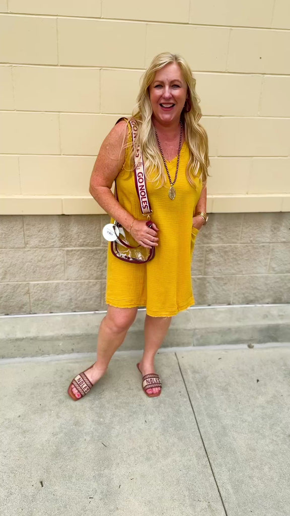 Sleeveless mustard cotton gauze dress with V-neckline, raw frayed edges, and front pockets. Lightweight and casual—ideal for Gameday or fall outings.
