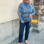 Baby blue long-sleeve top with a high neckline and geometric floral designs in yellow, green, and burgundy with decorative swirls.