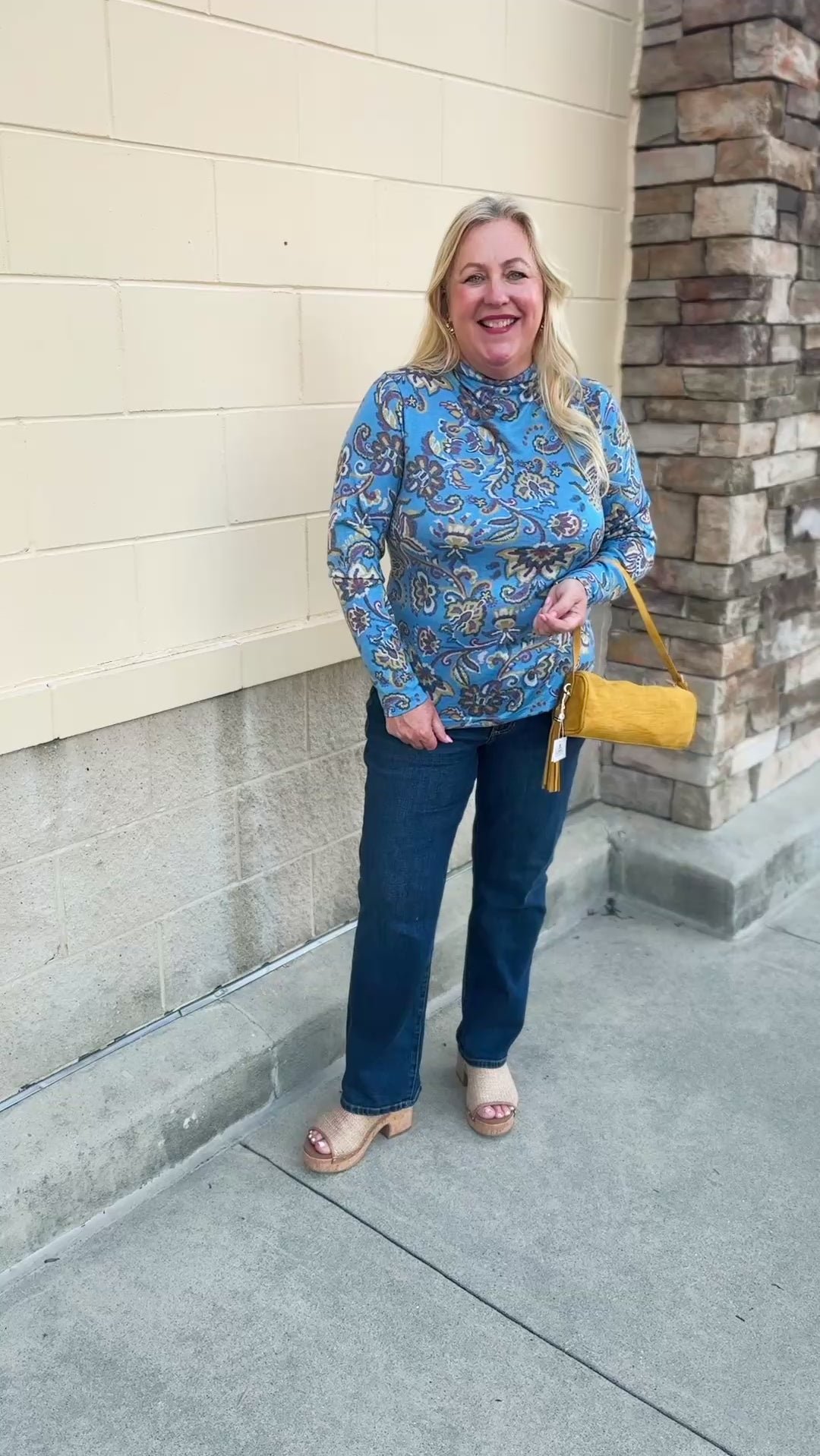 Baby blue long-sleeve top with a high neckline and geometric floral designs in yellow, green, and burgundy with decorative swirls.