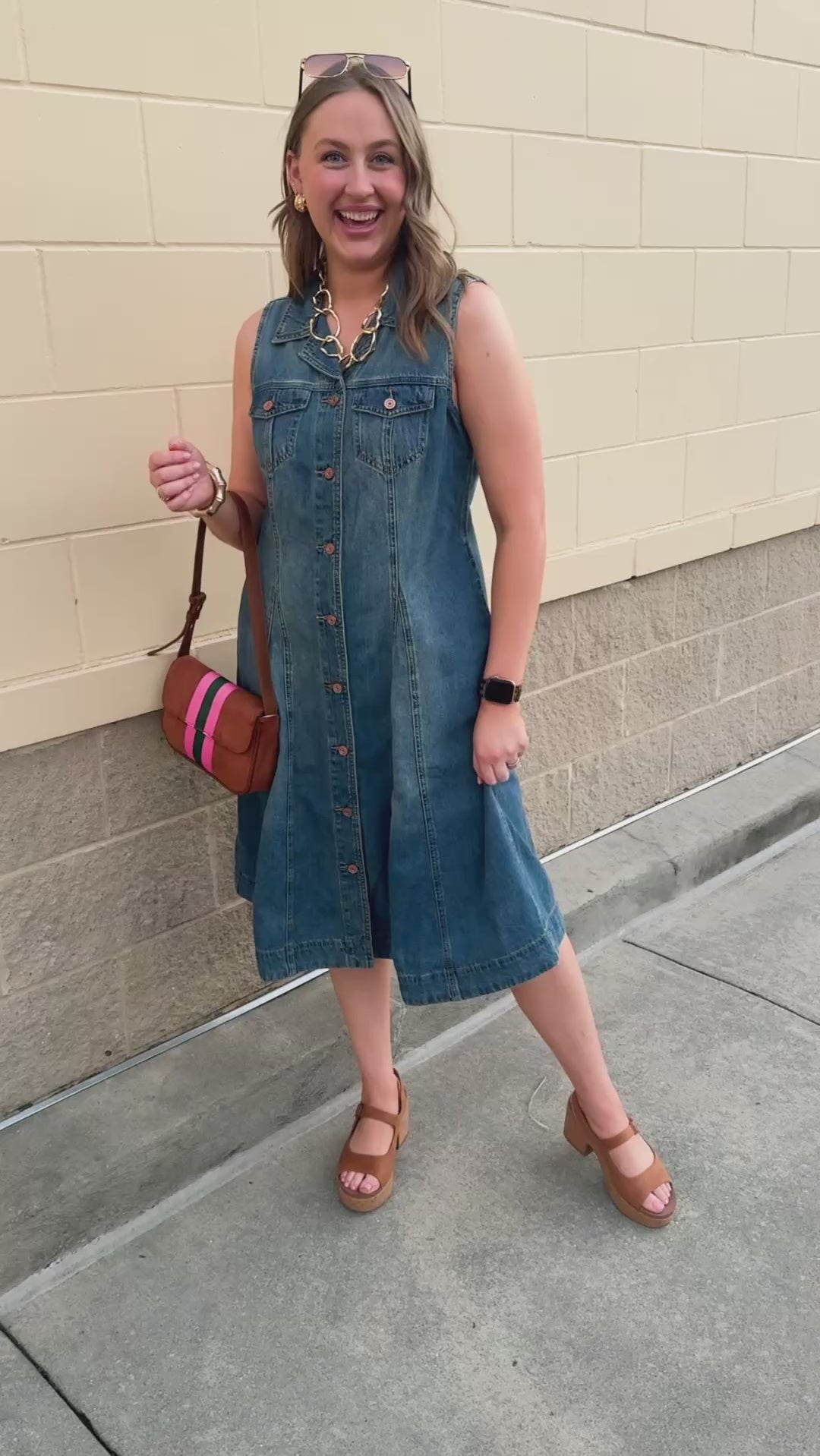 Sleeveless denim mini dress with a fold-over collar, full button-front closure, and two front pockets.