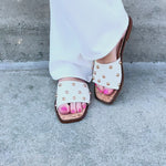White slide sandals with gold stud detail.