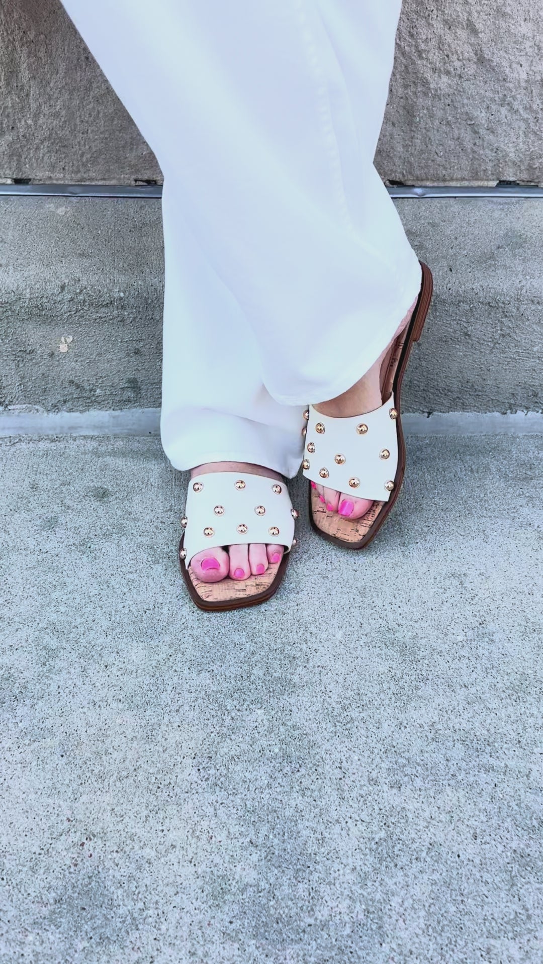 White slide sandals with gold stud detail.