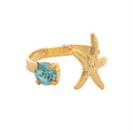 Open-front ring with a starfish and blue stone on a gold-tone band.