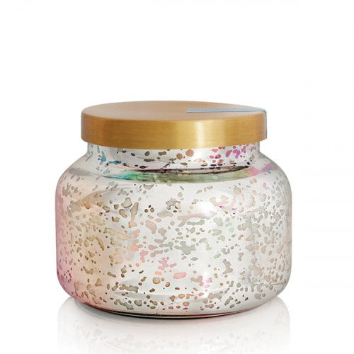 Capri Blue Volcano iridescent glass jar candle with steel lid, glowing with tropical citrus fragrance.
